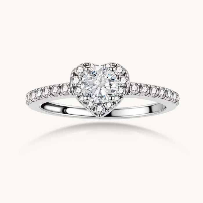 Heart-shaped halo ring with brilliant moissanite center stone surrounded by smaller crystals in sterling silver setting