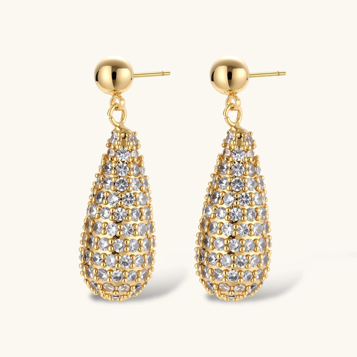 Gold-plated teardrop necklace and earrings covered in AAA cubic zirconia crystals on cream background.