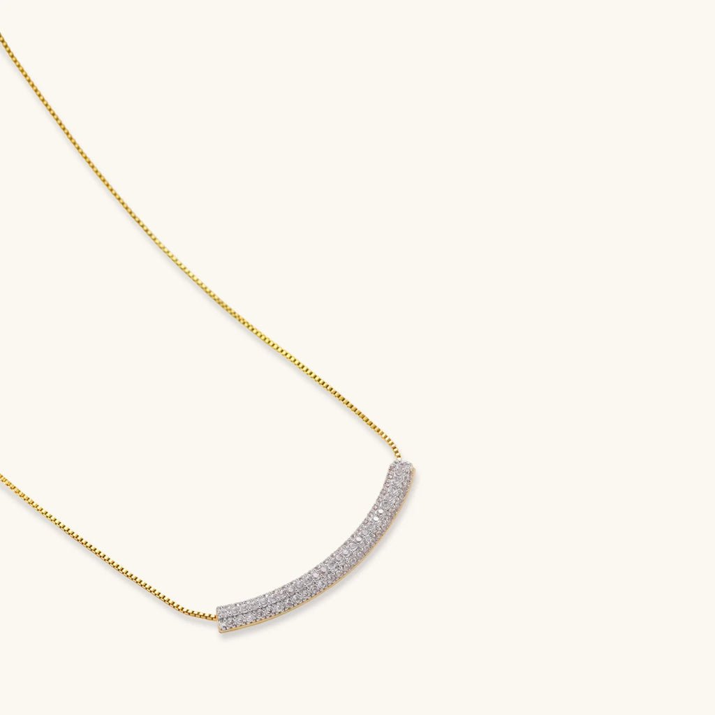 Gold-plated curved necklace, hoop earrings, and adjustable ring with pavé cubic zirconia stones on cream background.
