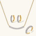 Gold-plated curved necklace, hoop earrings, and adjustable ring with pavé cubic zirconia stones on cream background.