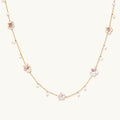 Gold vermeil chain with iridescent star-shaped baroque pearls and small round freshwater pearl drops on cream background.