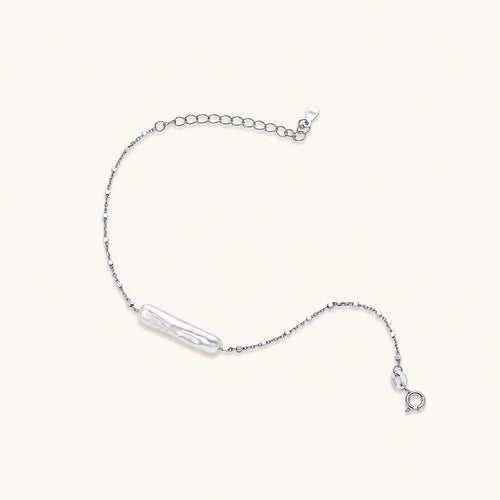 Minimalist bracelet with iridescent baroque pearl on rhodium-plated sterling silver chain against cream background