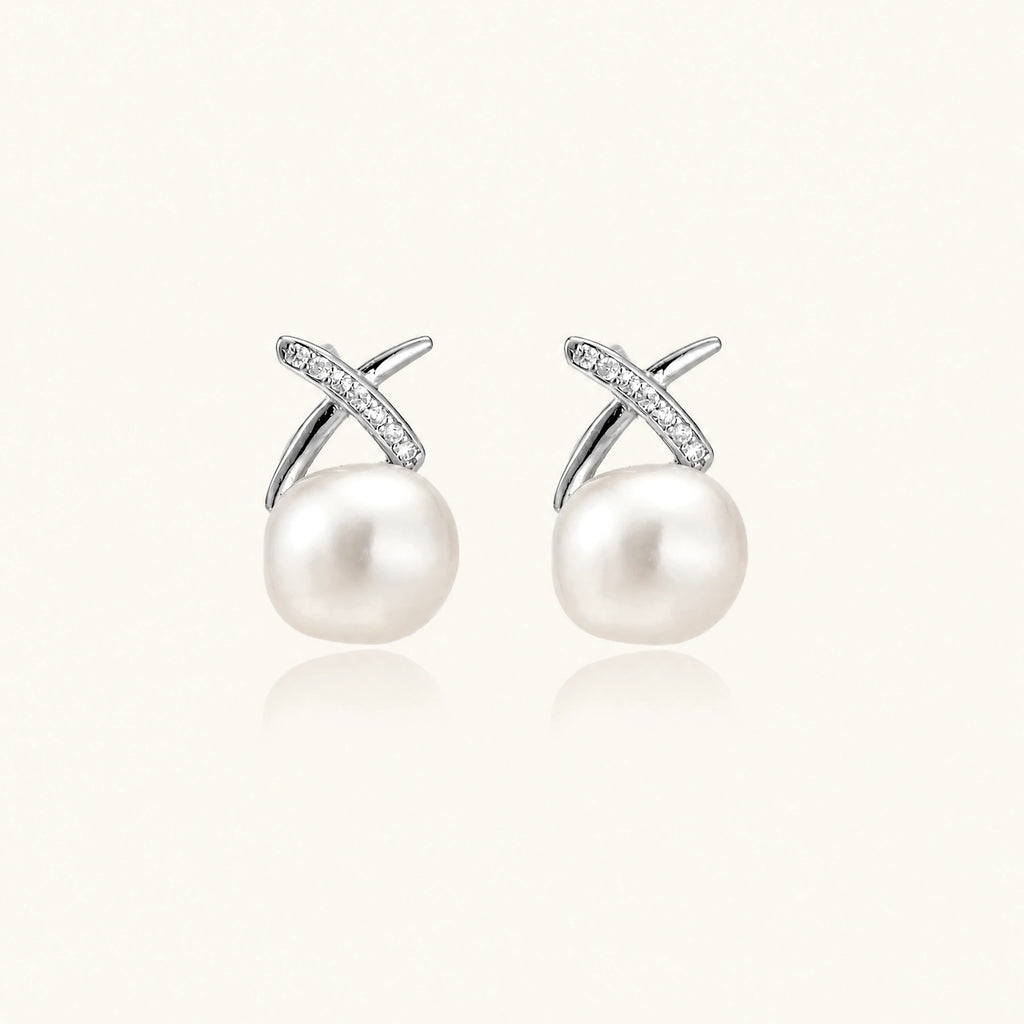 Rhodium-plated silver stud earrings with sparkling X design above lustrous round freshwater pearls on white background.